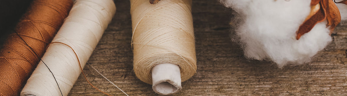 Threads with cotton on wooden surface.